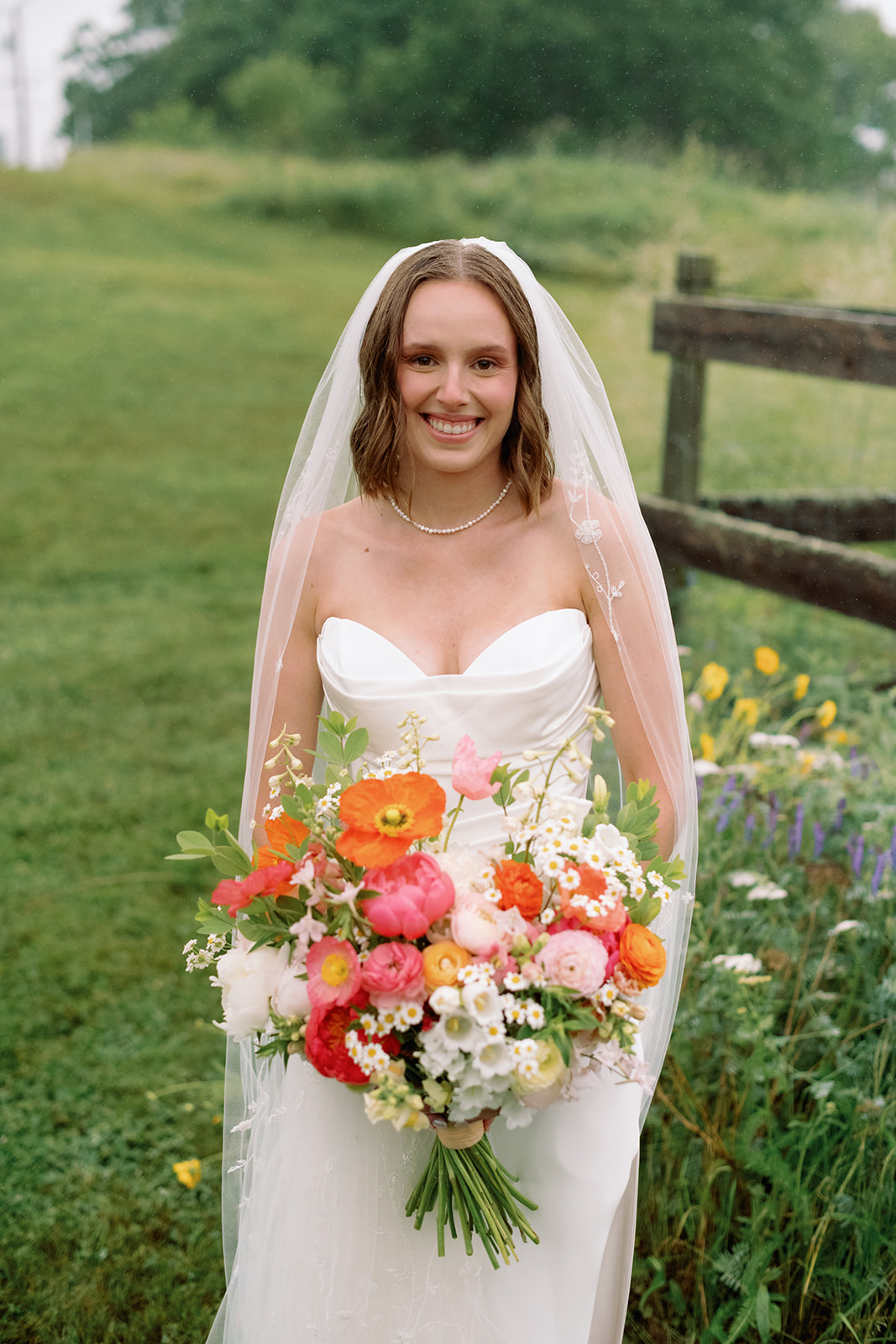 Bride carrying a farm-grown bouquet of ranunculus and poppies