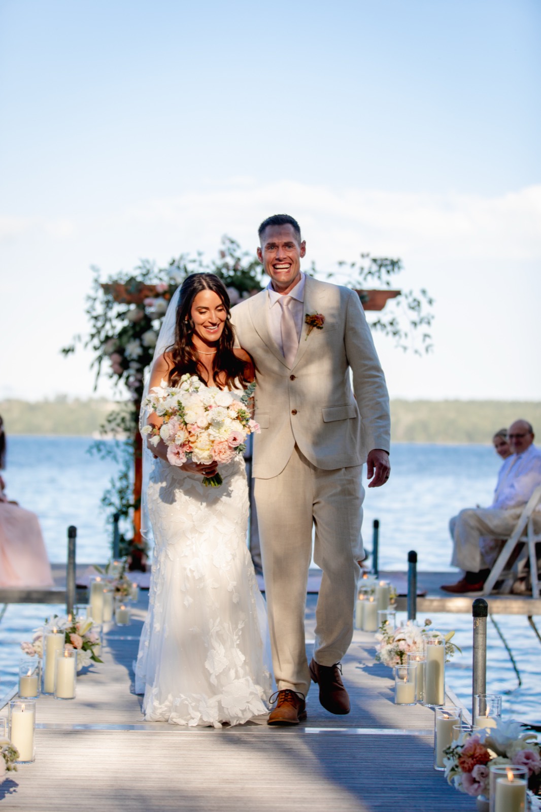 Ceremony on the dock — arch, candlelit aisle and the couple's walk back