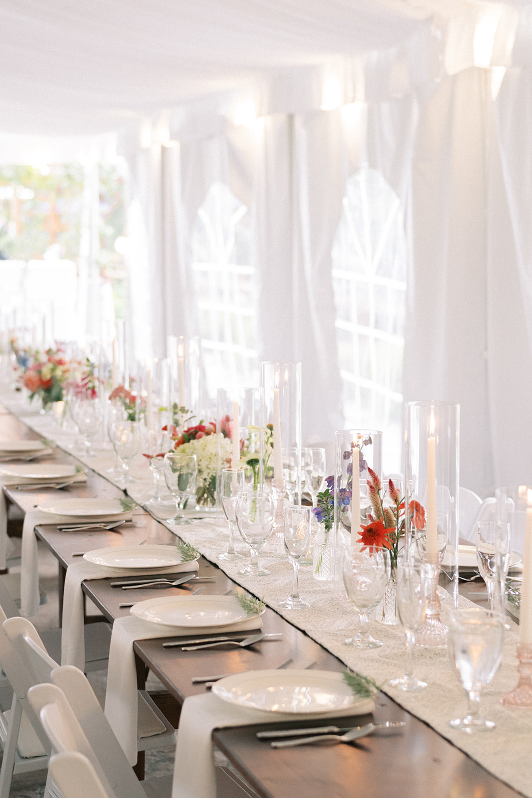 Sailcloth tent tablescape with bud vases and taper candles down the long table